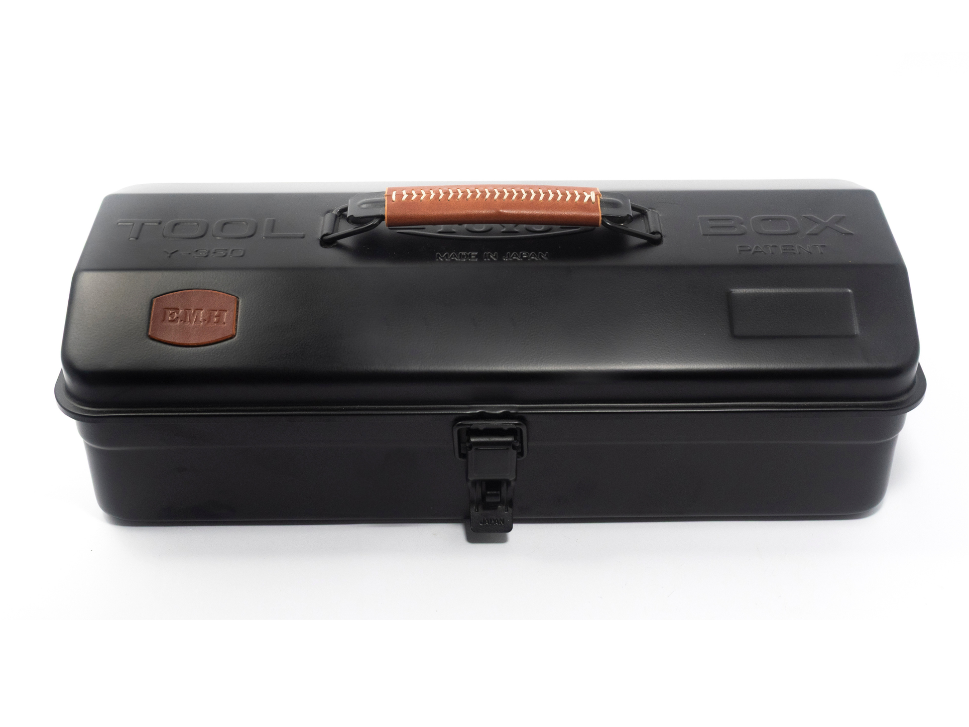 A black plastic tool box with a top handle, embossed 'TOOL BOX' text, and a small orange-brown brand patch on the left side, shown on a white background.