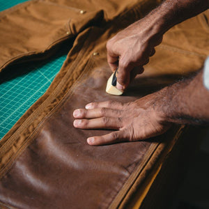 image of otter wax being applied to a pair of overalls